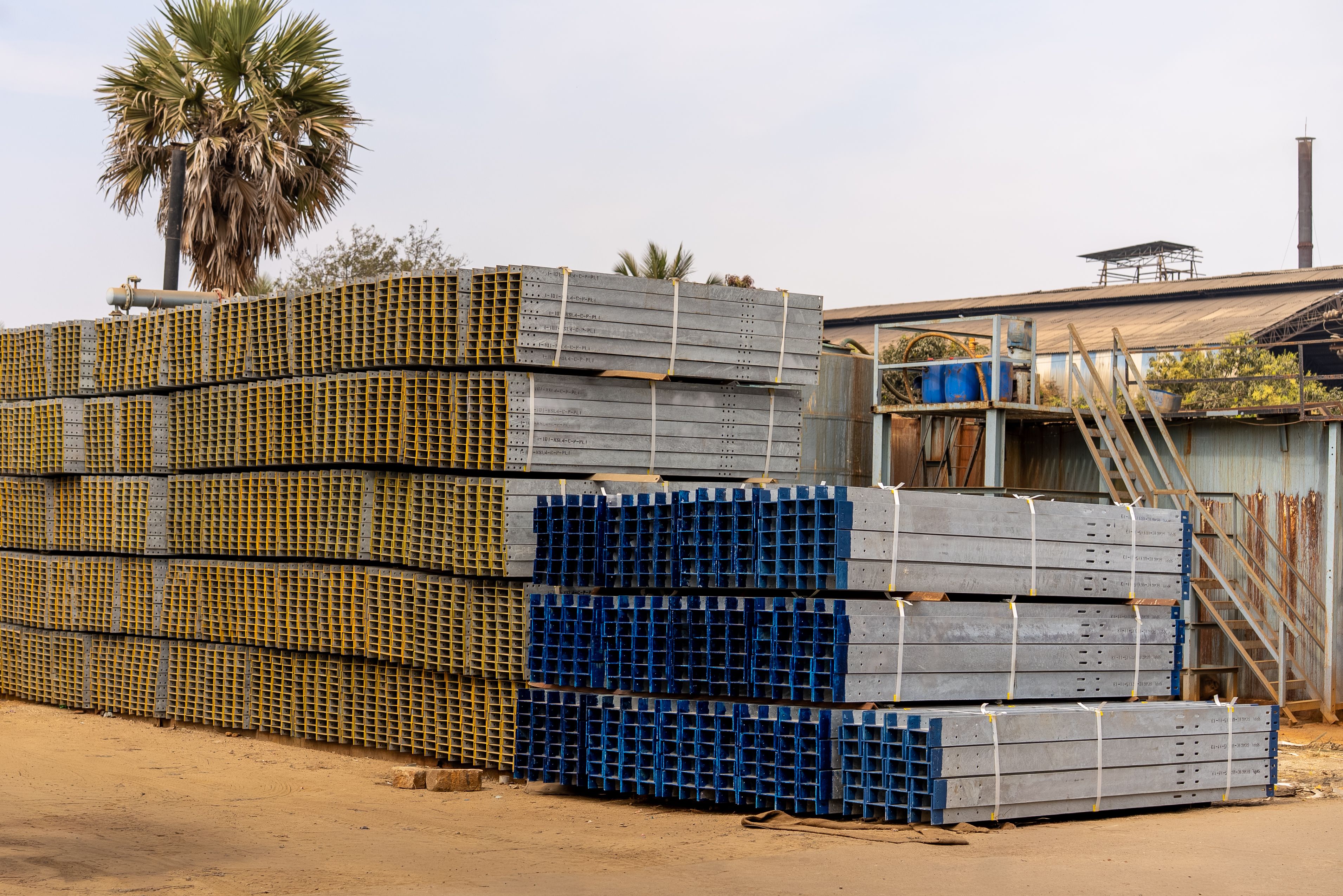 Stacked construction materials including steel sections in a yard